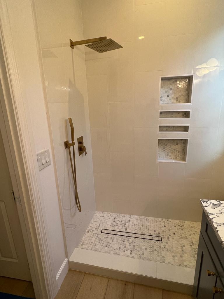 Curbless walk-in shower with brass fixtures, tiled niches and linear drain - Handyman Group SFL