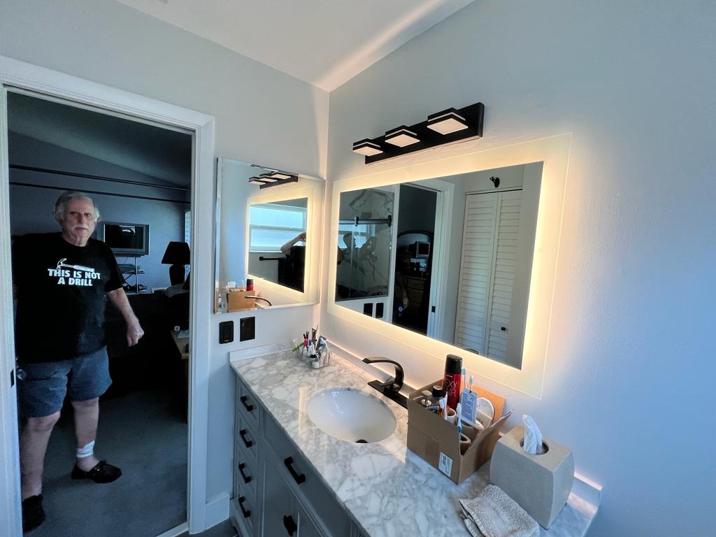 Marble-top vanity with backlit mirror and black light bar in a remodeled bathroom - Handyman Group SFL