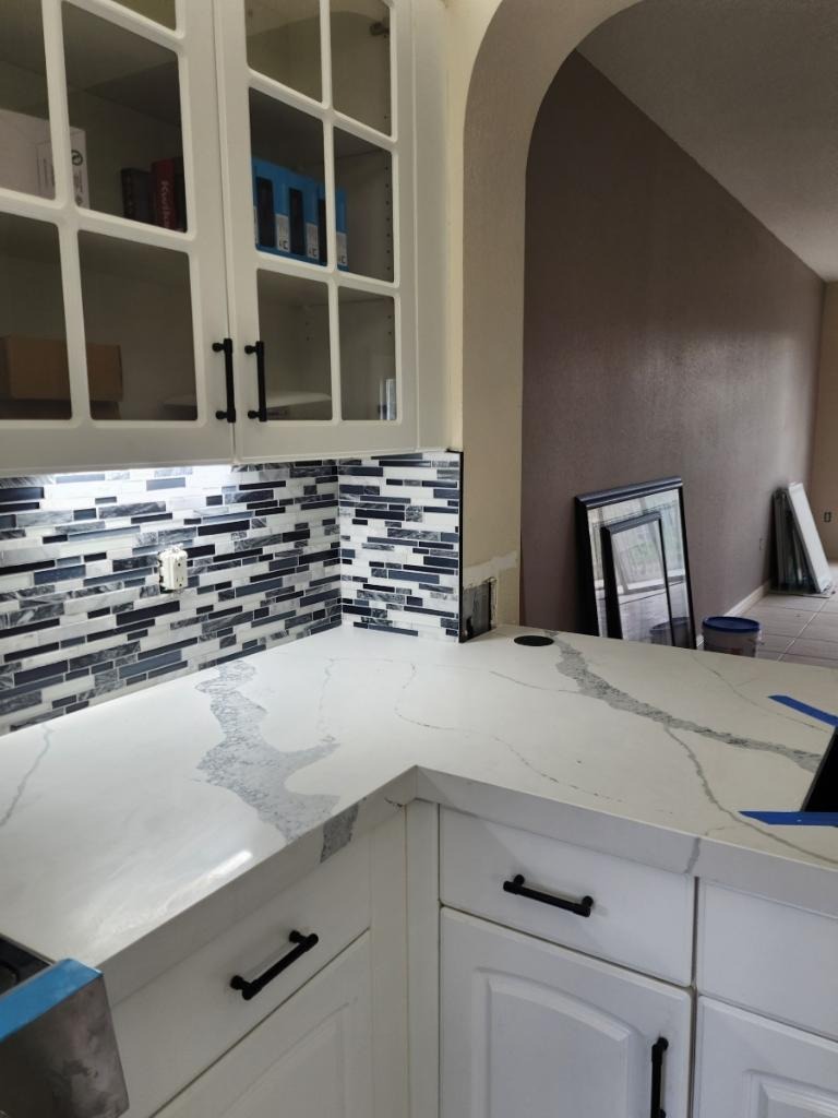 White quartz countertop corner with glass mosaic backsplash and glass-front cabinets - Handyman Group SFL