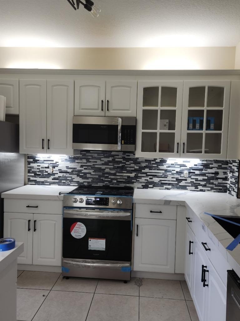 Kitchen remodel with white cabinets, stainless range and glass mosaic backsplash - Handyman Group SFL