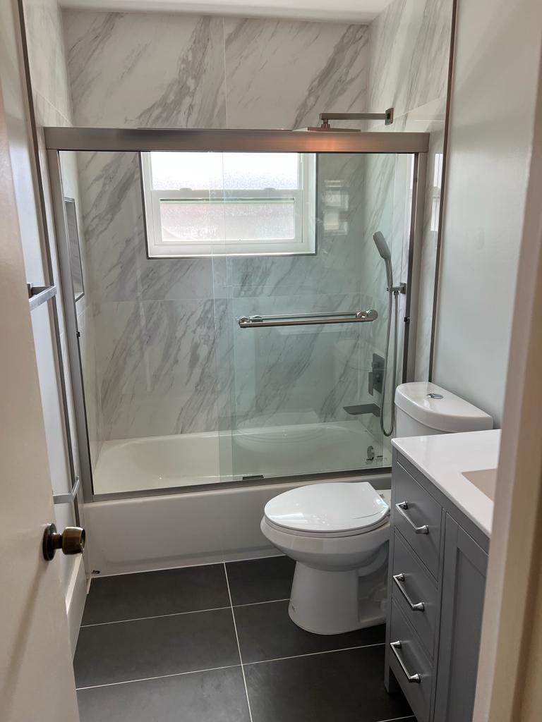 Remodeled bathroom with a marble-tiled glass shower and tub combo - Handyman Group SFL