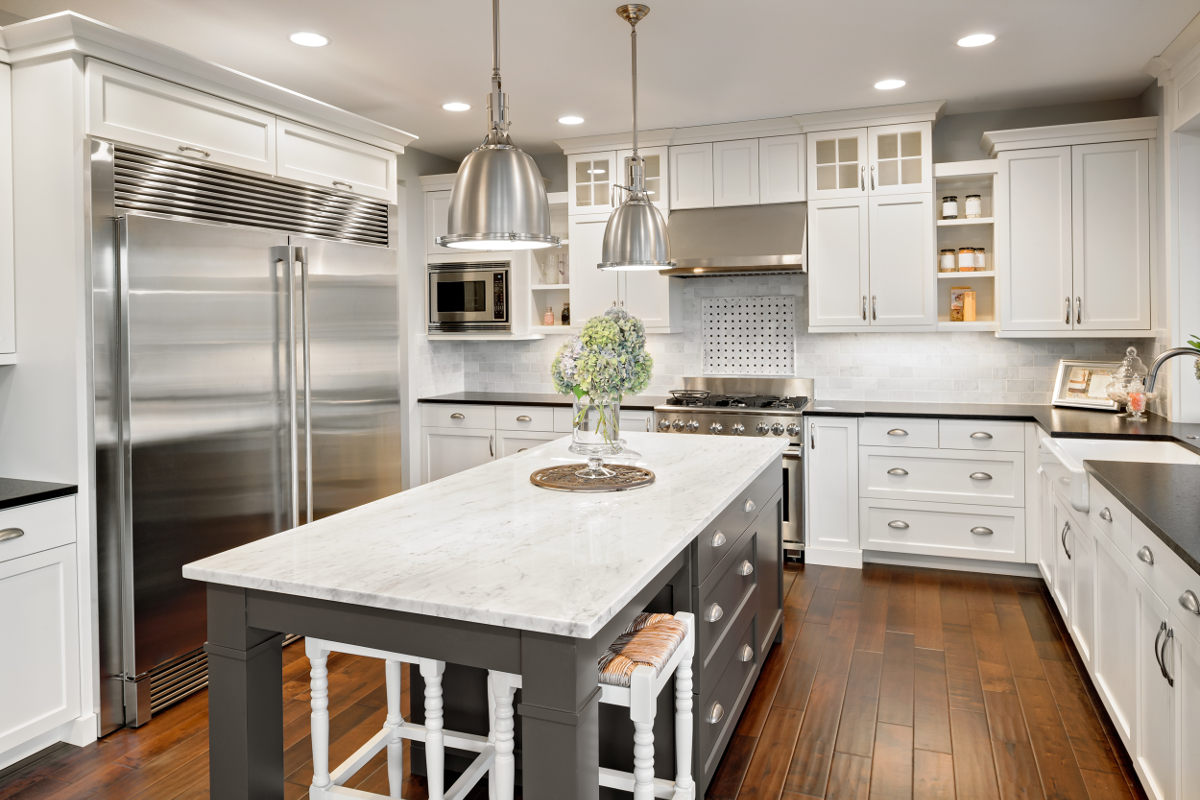 Remodeled kitchen with white cabinetry, stainless appliances and a marble island - Handyman Group SFL
