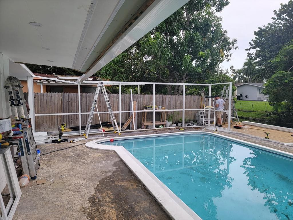 Pool screen enclosure frame rebuild in progress beside an in-ground pool - Handyman Group SFL
