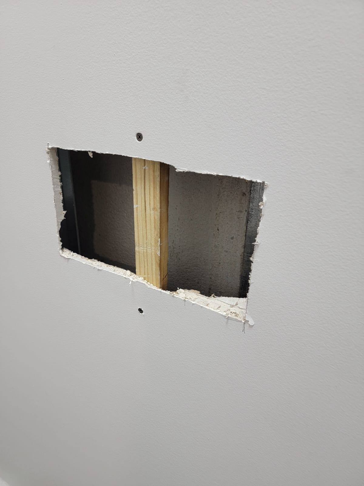 Rectangular drywall cutout exposing the wall stud before patching - Handyman Group SFL