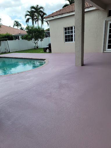 Resurfaced pool deck coating beside a screened patio and swimming pool - Handyman Group SFL